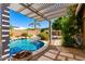 Inviting pool area featuring stone pavers and mature landscaping with a partial pergola at 23829 N 59Th Dr, Glendale, AZ 85310