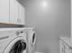 Bright laundry room featuring a washer and dryer set, along with upper and lower white cabinets for ample storage at 4671 N 185Th Ln, Goodyear, AZ 85395