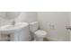 Cozy half bath featuring a pedestal sink, toilet and a round mirror at 5041 S 252Nd Ave, Buckeye, AZ 85326