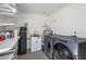 Well-equipped laundry room with modern washer and dryer, utility sink, and ample storage space at 8719 E San Marino Dr, Scottsdale, AZ 85258
