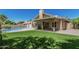 Home's backyard with covered patio, kitchen, pool and lawn at 8911 E Sutton Dr, Scottsdale, AZ 85260