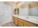 Bathroom with dual sinks, wood cabinets, tile floor, and a large mirror with lighting at 9649 E Holiday Way, Sun Lakes, AZ 85248