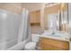 Well-lit bathroom featuring a tub/shower combo with a shower curtain and wooden cabinets at 9649 E Holiday Way, Sun Lakes, AZ 85248