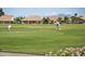 Scenic view of golfers putting on a well-manicured green with houses and mountains in the background at 9649 E Holiday Way, Sun Lakes, AZ 85248