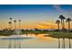 Picturesque sunset view over a scenic pond with a fountain, palm trees, and distant mountains at 9649 E Holiday Way, Sun Lakes, AZ 85248