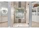 Elegant shower room featuring neutral tiling, glass brick accent wall and glass shower door with a view of the vanity at 9736 E Ironwood Dr, Scottsdale, AZ 85258