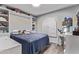 Charming bedroom with wood-look floors, featuring a comfortable bed, a window with white shutters and a desk at 9736 E Ironwood Dr, Scottsdale, AZ 85258