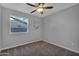 Neutral bedroom with a ceiling fan, plush carpeting, and ample natural light from the window at 10743 W Frier Dr, Glendale, AZ 85307