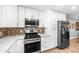 Updated kitchen featuring stainless steel appliances, stylish backsplash, and bright white cabinets at 1744 E Huber St, Mesa, AZ 85203