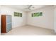 Bright bedroom showcasing tile flooring, a ceiling fan, a storage cabinet, and two sunlit windows at 2219 W Catalina Dr, Phoenix, AZ 85015