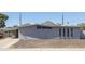 Exterior view of a single-story house with a gravel yard, gray stucco exterior, and unique vertical window accents at 2346 E Sylvia St, Phoenix, AZ 85022
