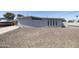 View of the side of a gray stucco house with a gravel yard and a boat parked under the carport at 2346 E Sylvia St, Phoenix, AZ 85022