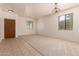 Bright, carpeted living room with natural light and neutral tones, adjacent to tiled entry at 44188 W Cydnee Dr, Maricopa, AZ 85138