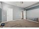 Spacious carpeted bedroom featuring a ceiling fan and three white doors at 10945 E Storia Ave, Mesa, AZ 85212