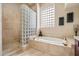 Bathroom featuring a walk-in shower with glass block and a luxurious soaking tub at 11448 E Blue Sky Dr, Scottsdale, AZ 85262