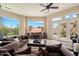 Cozy living room featuring comfortable seating, a ceiling fan, large windows, and views of the desert landscape at 11448 E Blue Sky Dr, Scottsdale, AZ 85262