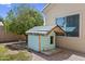 A lovely blue dog house sits in a patio beside a tan home with a window and a light brick wall at 119 S Monterey St, Gilbert, AZ 85233