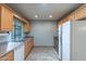 Kitchen with wood cabinetry, stainless steel sink and white appliances at 13261 N 110Th Ave, Sun City, AZ 85351