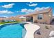 Beautiful backyard with a curved pool, artificial turf, desert landscaping, outdoor kitchen and covered patio at 15663 S 183Rd Dr, Goodyear, AZ 85338