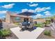 Landscaped backyard featuring a patio dining area with an umbrella, artificial turf, and desert landscaping at 15663 S 183Rd Dr, Goodyear, AZ 85338
