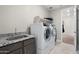 The laundry room has a sink with granite countertop and modern washer and dryer appliances at 15663 S 183Rd Dr, Goodyear, AZ 85338