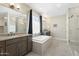 Luxurious bathroom featuring dual vanities, a soaking tub, and a separate glass-enclosed shower at 15663 S 183Rd Dr, Goodyear, AZ 85338