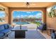 View from the covered patio of the pool and landscaped backyard featuring stylish outdoor furniture and a mounted television at 15663 S 183Rd Dr, Goodyear, AZ 85338