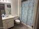 Bright bathroom featuring a clean white vanity, mirror, and a shower with a light blue patterned shower curtain at 17823 N 99Th Dr, Sun City, AZ 85373