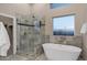 Bathroom with a glass shower, modern tub, marble accents and bright natural lighting at 18401 N 14Th St, Phoenix, AZ 85022
