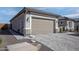 Attached two-car garage with a light brown door, adjacent to well maintained landscaping at 20210 N Wagner Wash Dr, Buckeye, AZ 85396