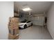 This garage features a modern white car, epoxy flooring, and overhead storage for organization at 20210 N Wagner Wash Dr, Buckeye, AZ 85396