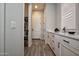 Hallway with white cabinets, quartz countertop, storage shelves, and tile flooring at 20210 N Wagner Wash Dr, Buckeye, AZ 85396