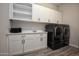 Modern laundry room featuring white cabinets and black washer/dryer appliances for efficient cleaning at 20210 N Wagner Wash Dr, Buckeye, AZ 85396