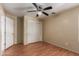 This is a simple bedroom with wood floors, closet, ceiling fan, and neutral-colored walls at 2122 W Alta Vista Rd, Phoenix, AZ 85041