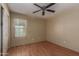 This is a simple bedroom with wood floors, closet, window with blinds, ceiling fan, and neutral-colored walls at 2122 W Alta Vista Rd, Phoenix, AZ 85041