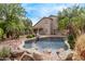 Landscaped back yard has a pool and relaxing water feature among lush greenery at 21373 N 94Th Ave, Peoria, AZ 85382