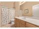 Bright bathroom features a wide mirror, vanity, sink, toilet, and shower with seashell-themed curtain at 21373 N 94Th Ave, Peoria, AZ 85382