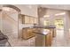 Bright kitchen with island, tile floors, light wood cabinets, and staircase access at 21373 N 94Th Ave, Peoria, AZ 85382