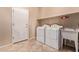 Functional laundry room has tile floors and features both a washing machine and dryer at 21373 N 94Th Ave, Peoria, AZ 85382