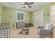 Neutral color bedroom with a window, ceiling fan, and a grey cushioned rocking chair at 21918 E Maya Rd, Queen Creek, AZ 85142