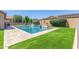 Inviting backyard pool with stylish tiling, complemented by lush artificial turf and mature landscaping at 21918 E Maya Rd, Queen Creek, AZ 85142