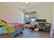 Bright bedroom with wood floors, a colorful bed, and a window view of the home across the street at 2221 W Madisen Marie Ave, Queen Creek, AZ 85144