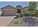 Inviting home with a brick driveway, featuring a well-kept yard with mature trees, and trimmed bushes at 2221 W Madisen Marie Ave, Queen Creek, AZ 85144