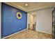 An inviting living space with wood floors, a blue accent wall, a clock, and a doorway to another room at 2221 W Madisen Marie Ave, Queen Creek, AZ 85144