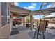 Covered patio features outdoor seating, BBQ, and beautiful lawn, all enhanced by patio rugs and umbrellas at 2412 W Camp River Rd, San Tan Valley, AZ 85144