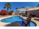 Backyard pool with lounge chairs, patio umbrella, barbecue, and tropical foliage at 24806 W Hidalgo Dr, Buckeye, AZ 85326