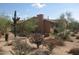 Tan single-story home featuring desert landscaping with native cactus, plants and trees at 27239 N 64Th Way, Scottsdale, AZ 85266