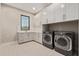 Well-lit laundry room featuring modern front-load washer and dryer, stylish cabinets, and an attractive patterned tile floor at 31226 N Granite Reef Rd, Scottsdale, AZ 85266