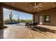 Inviting covered patio with wooden ceiling, ceiling fan, dining set, and pool surrounded by native desert vegetation at 31226 N Granite Reef Rd, Scottsdale, AZ 85266