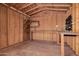 Interior of the storage shed with wooden walls, shelves, a workbench and overhead lighting at 3540 E Dolphin Ave, Mesa, AZ 85204